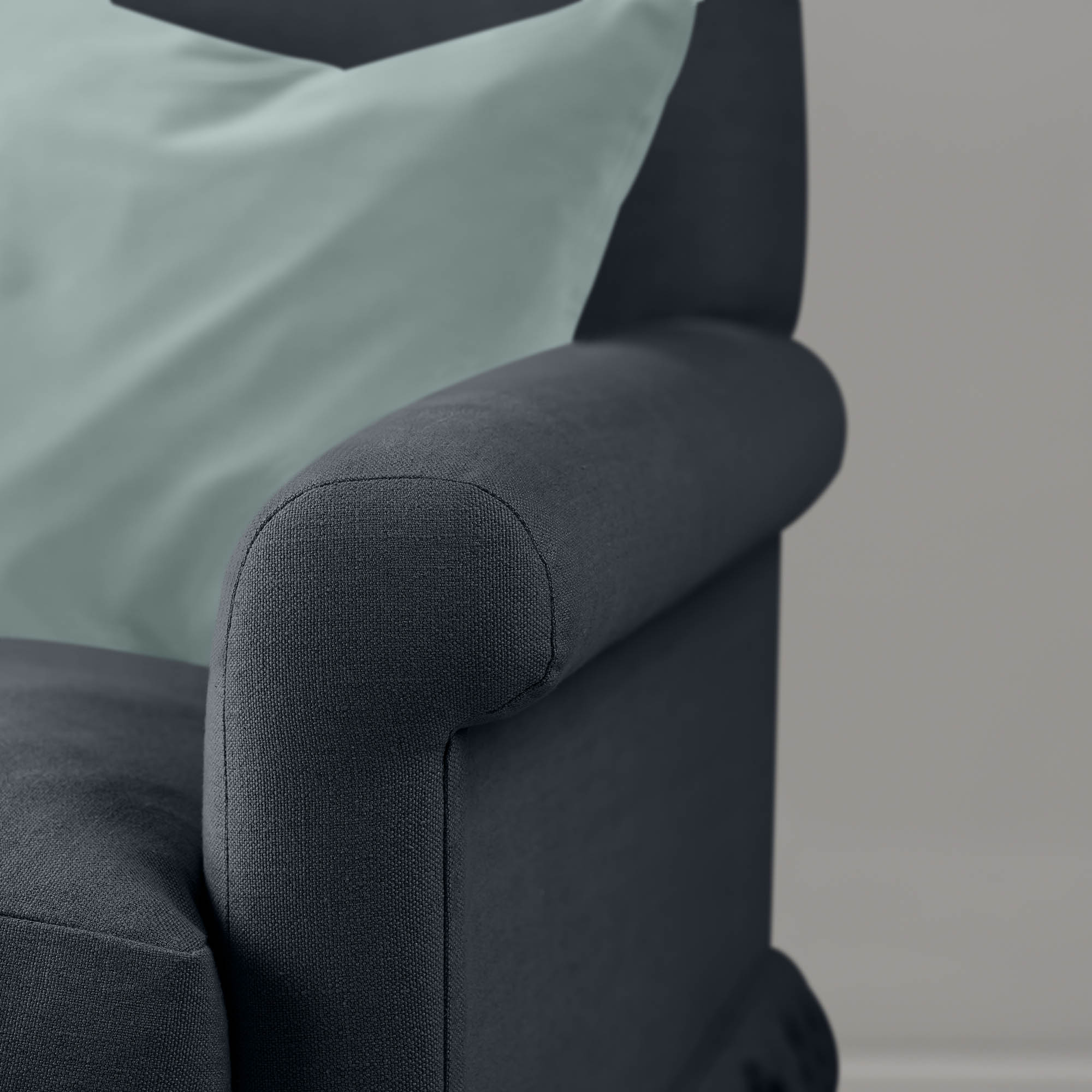 Detail of the armrest on the Midnight Curtain Call sofa by NiX styled with a contrasting cushion.