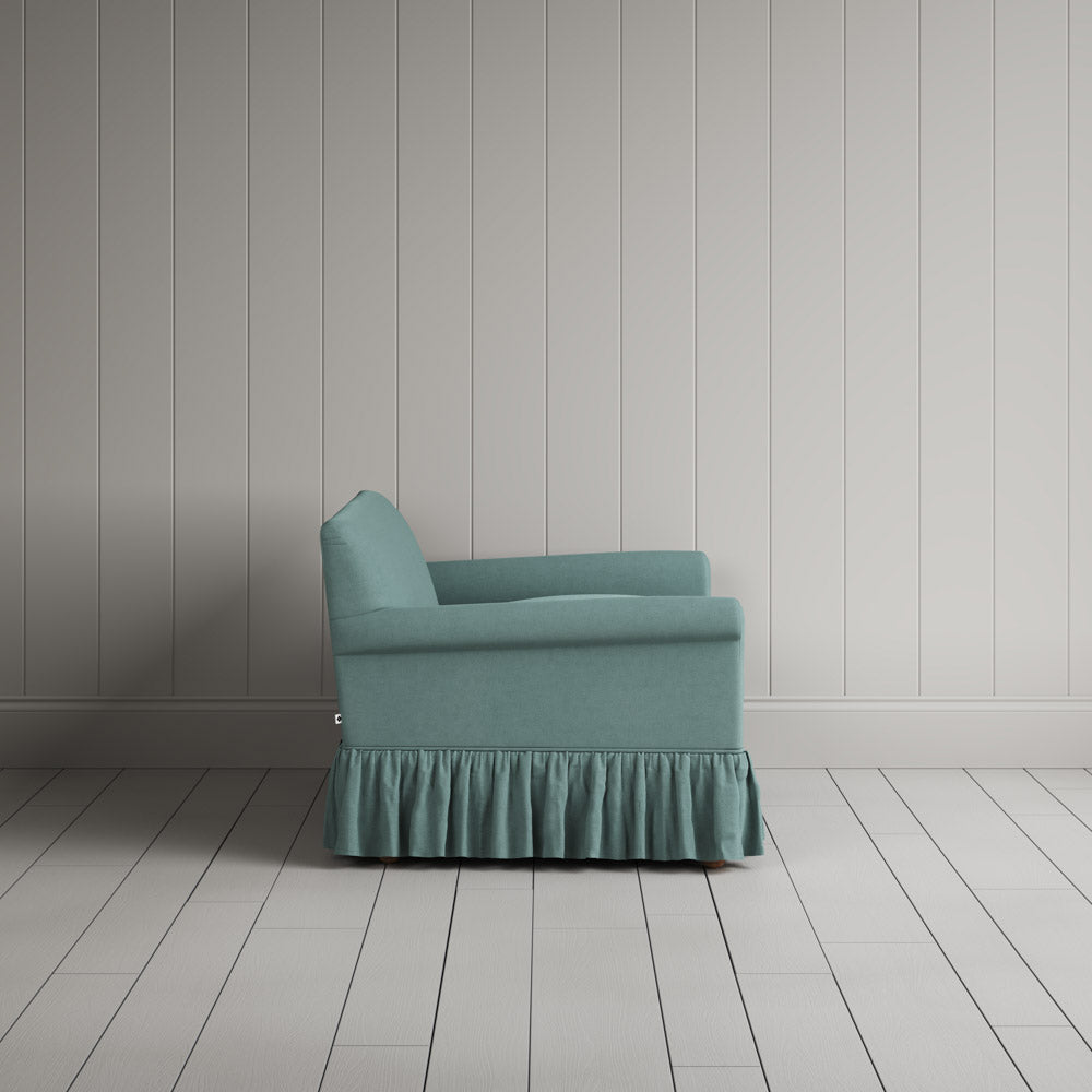 Side profile of Curtain Call love seat in cerulean linen with ruffled skirt by Nicola Harding