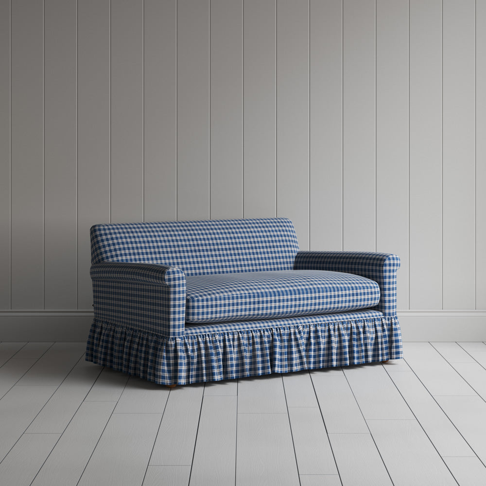 Angled shot of a blue and brown plaid upholstered love seats by Nicola Harding.