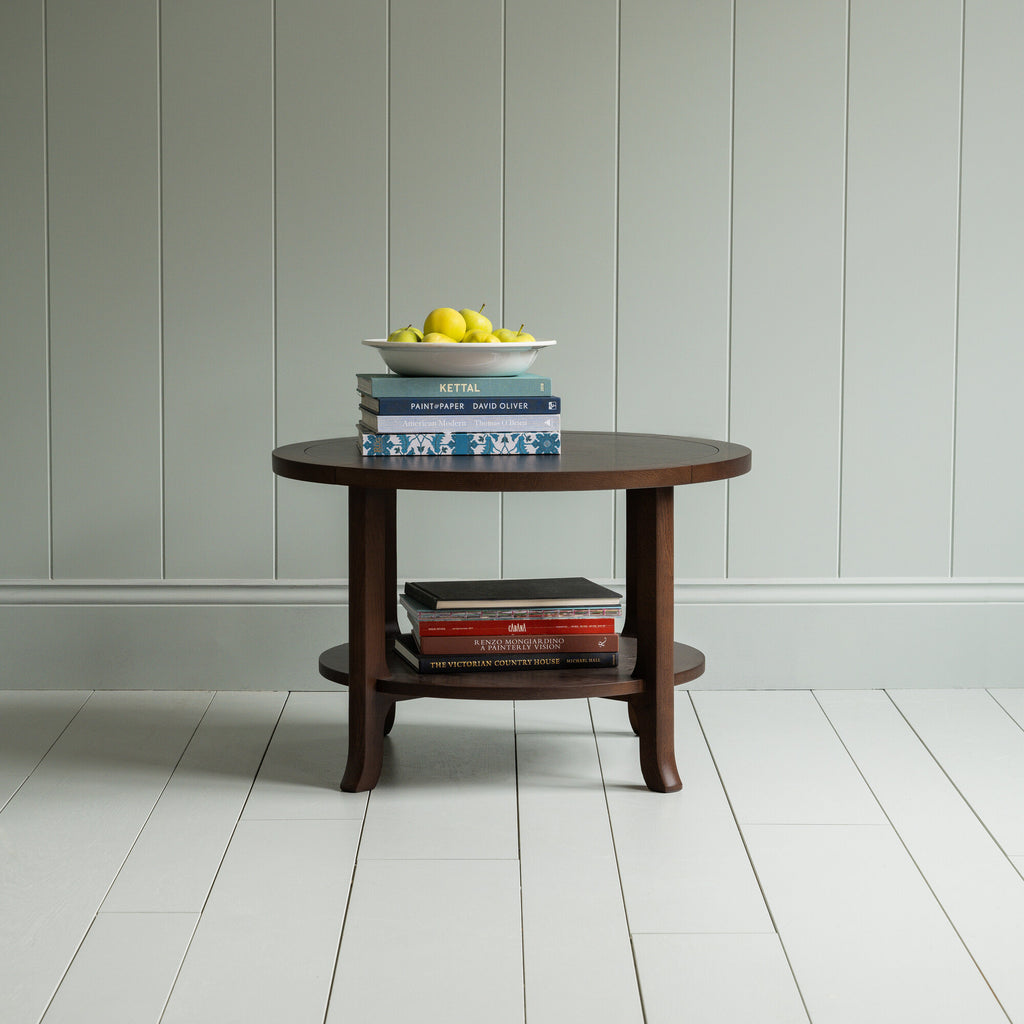 Round Perk coffee table in smoky stained oak with books and a plate of fruits, by Nicola Harding & Co.