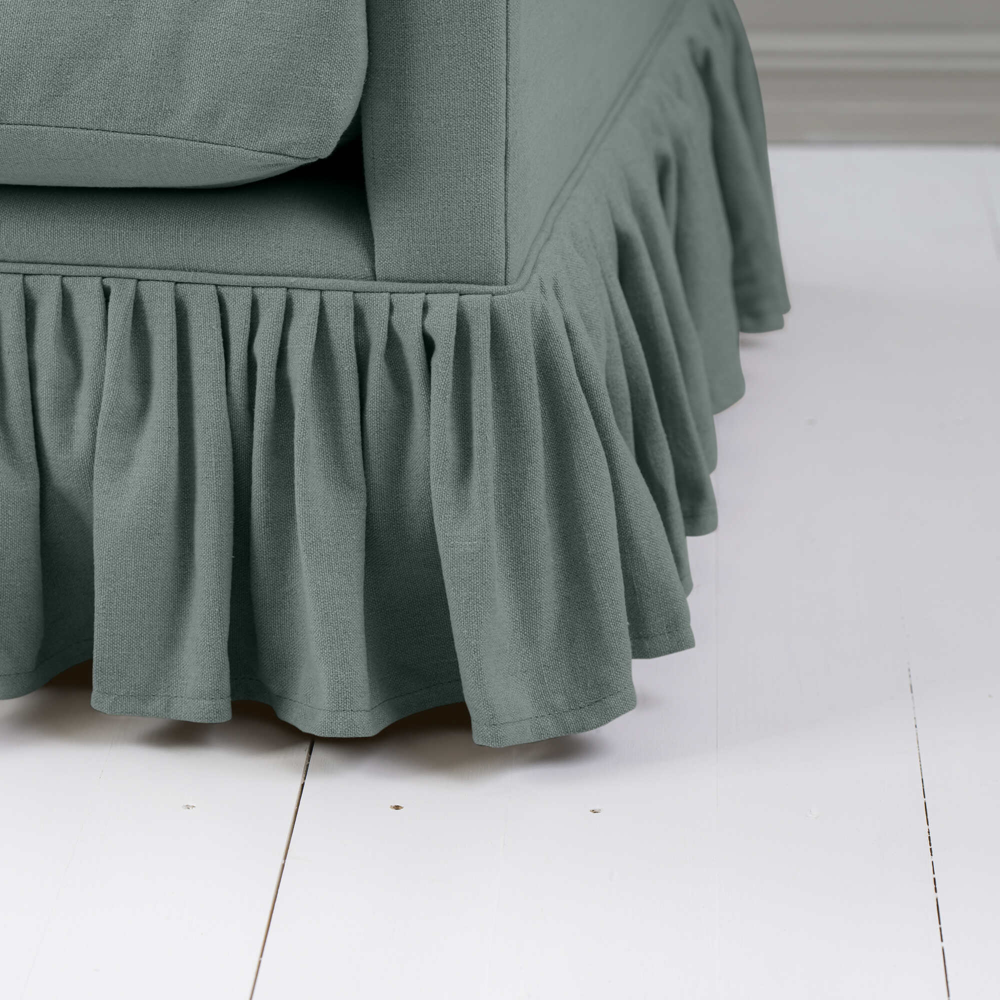 Curtain Call Love Seat close-up detail of the gathered ruffled skirt base and sea teal green linen fabric folds