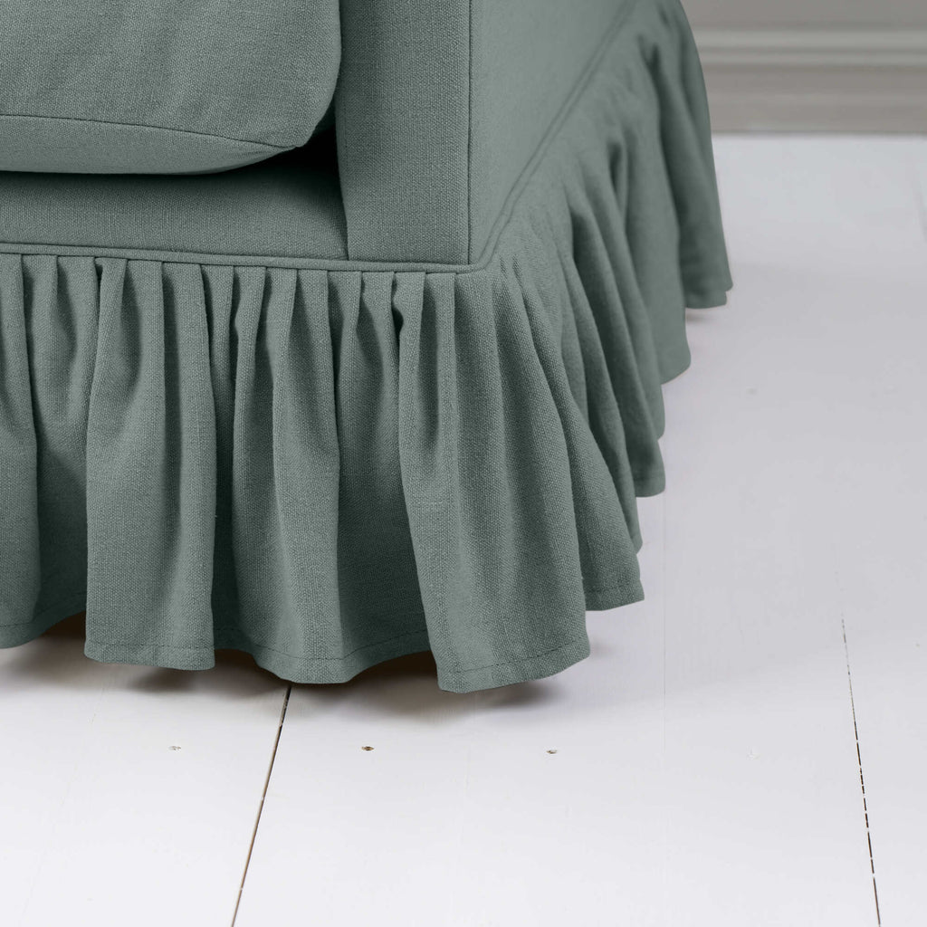 Curtain Call Love Seat close-up detail of the gathered ruffled skirt base and sea teal green linen fabric folds