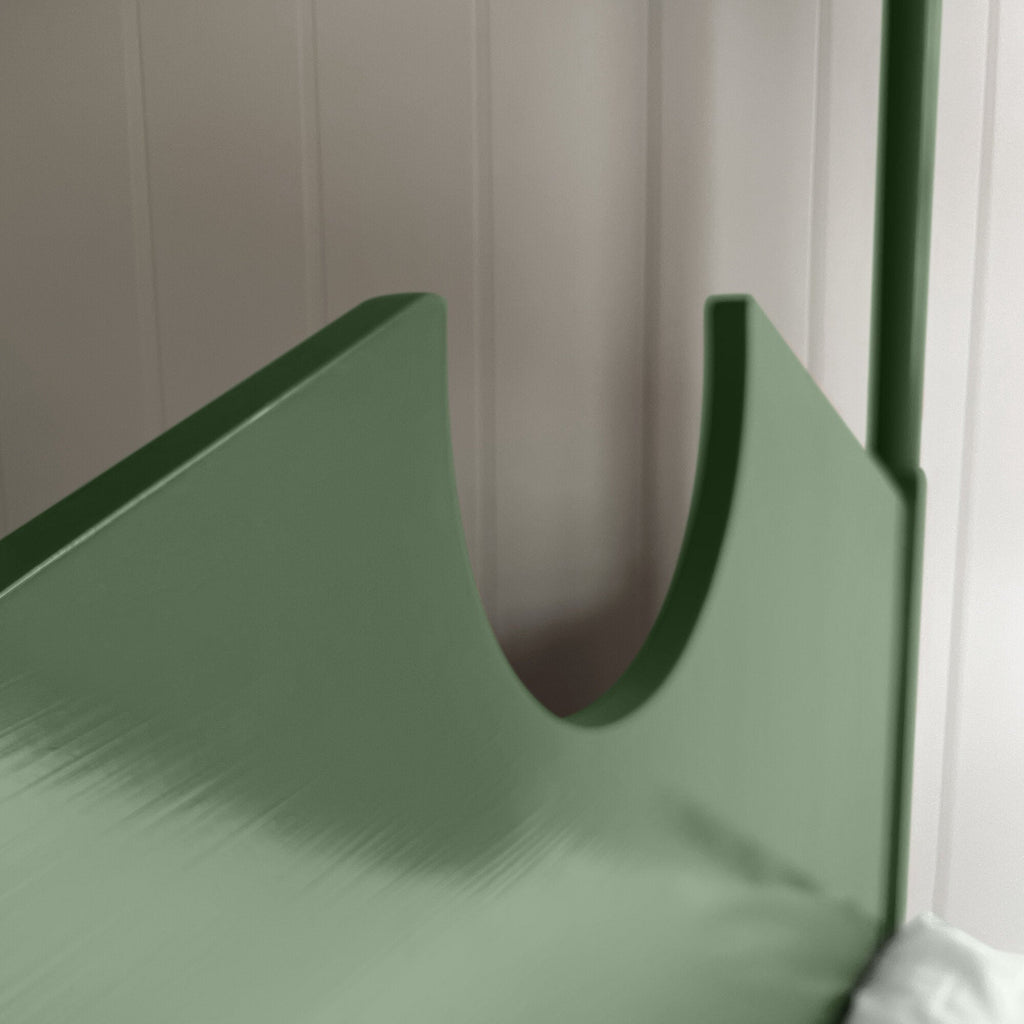 A green metal bed with a white pillow, providing comfort and style to any bedroom decor.