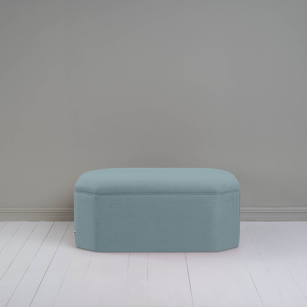 Small light blue ottoman in room with gray wall, adding cozy touch to modern decor.