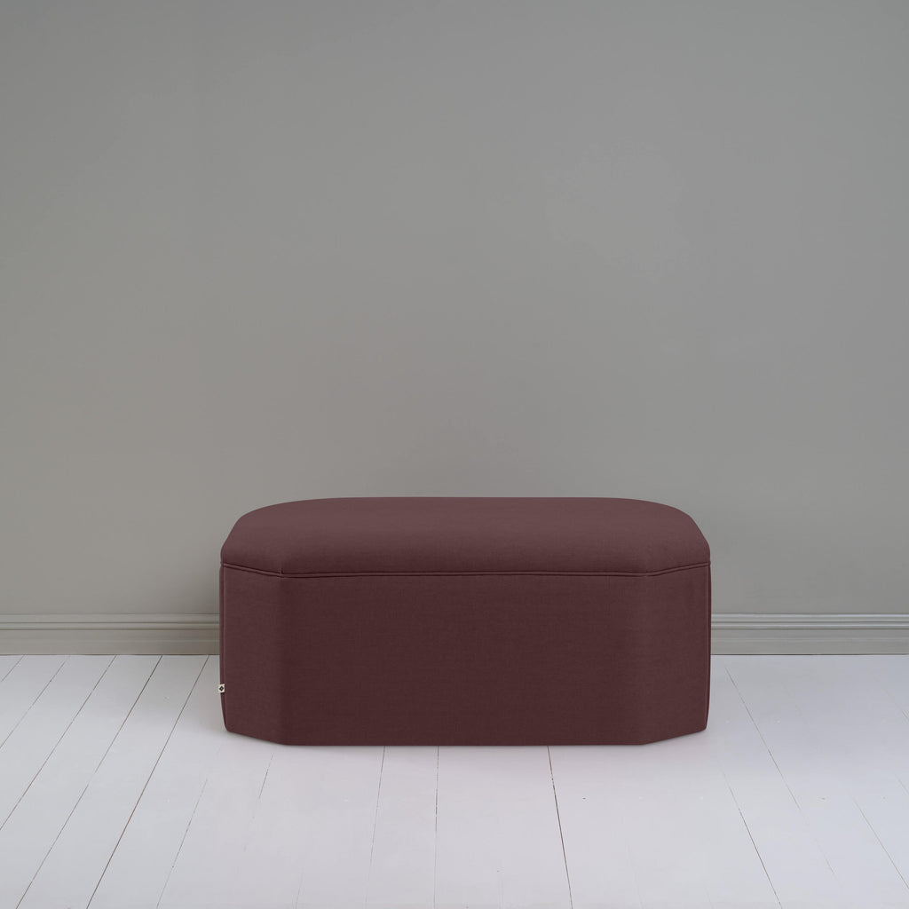 Small dark brown ottoman in room with gray wall, adding cozy touch to modern decor.