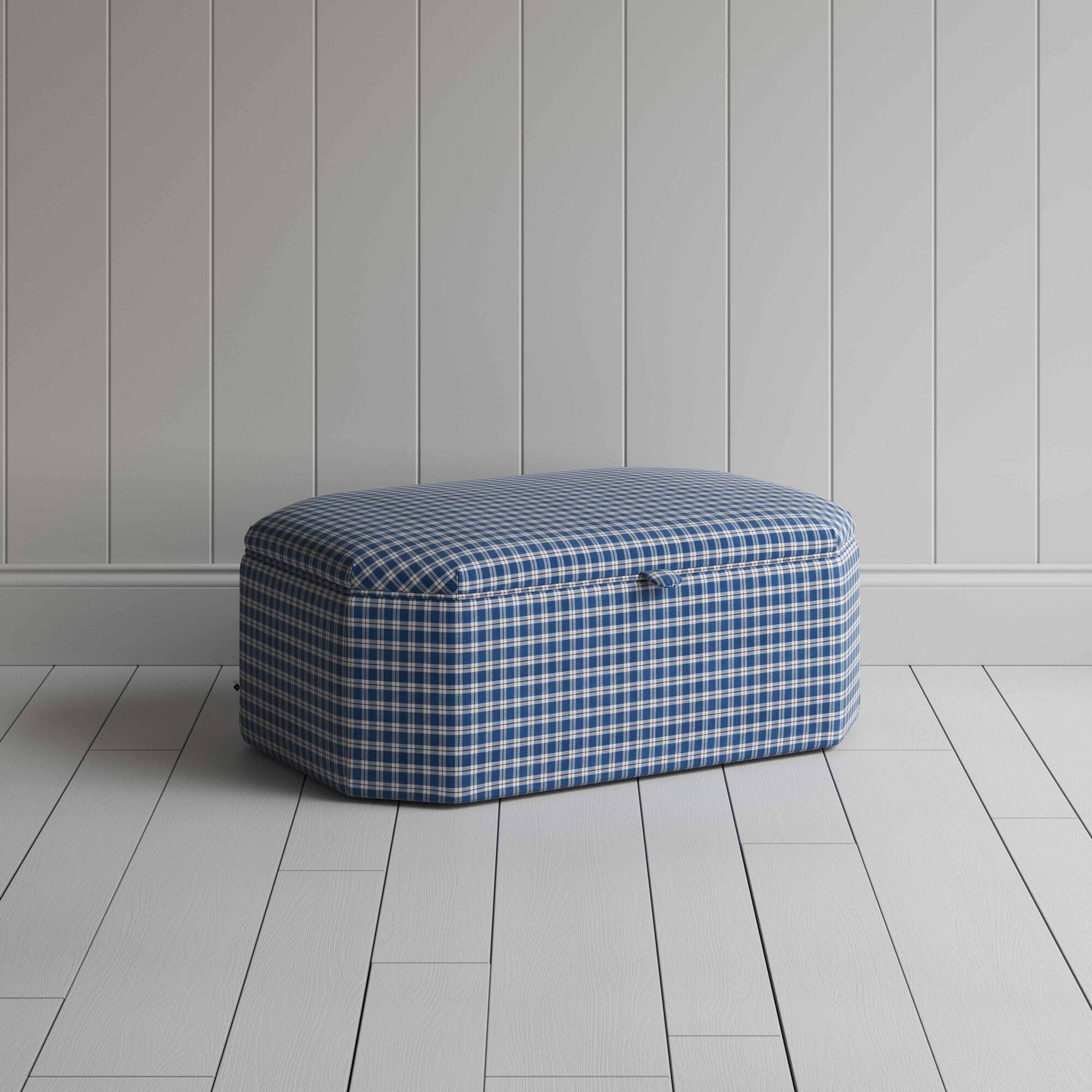 A blue and white checkered ottoman on a wooden floor, providing a stylish and organized solution.