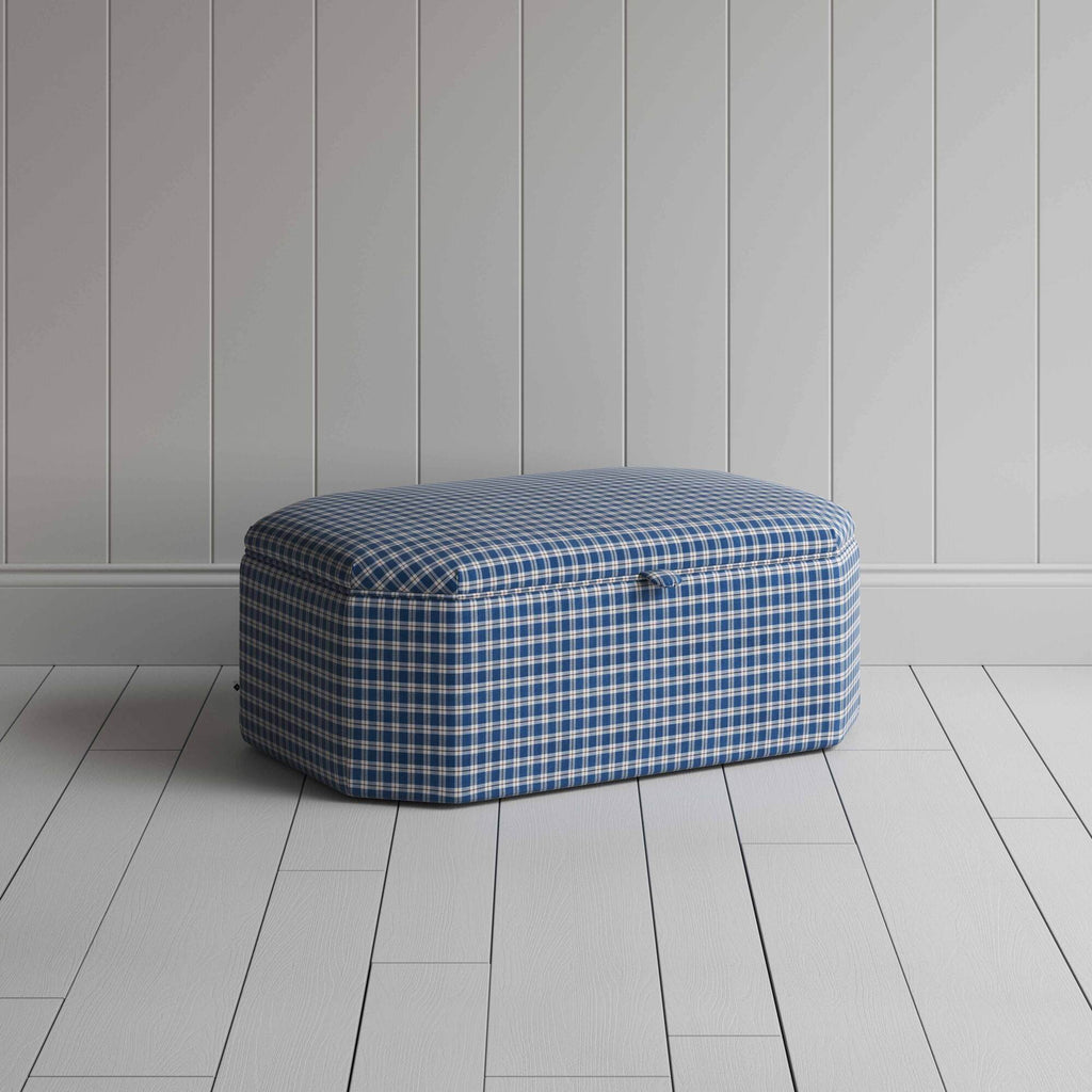 A blue and white checkered ottoman on a wooden floor, providing a stylish and organized solution.