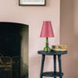 Ditsy Tall Tapered Lamp Shade in Burgundy with Pink Trim, With Ditsy Ceramic Table Lamp Base in Olive Green, On a Spindle Side Table, Carbon Black, With Couple of Books - Nicola Harding