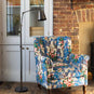 Focused Empire Lamp Shade in Waxed Brass with Rolled Edge, With Brass Floor Lamp, Next to a Beautiful High Back Arm Chair - Nicola Harding