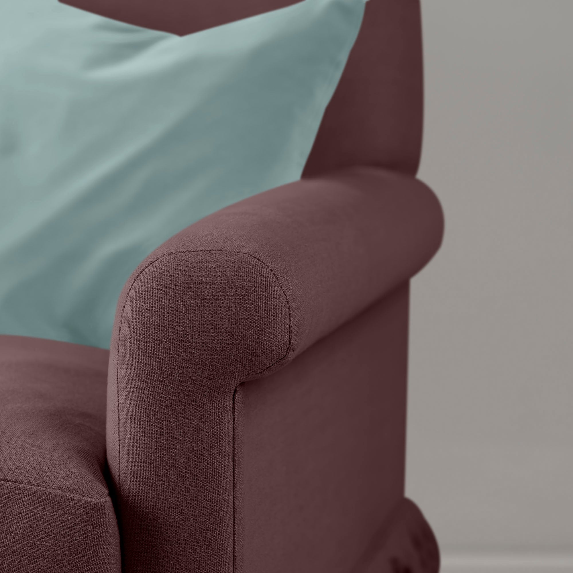 Detail of the armrest on the Damson Curtain Call sofa by NiX styled with a contrasting cushion.