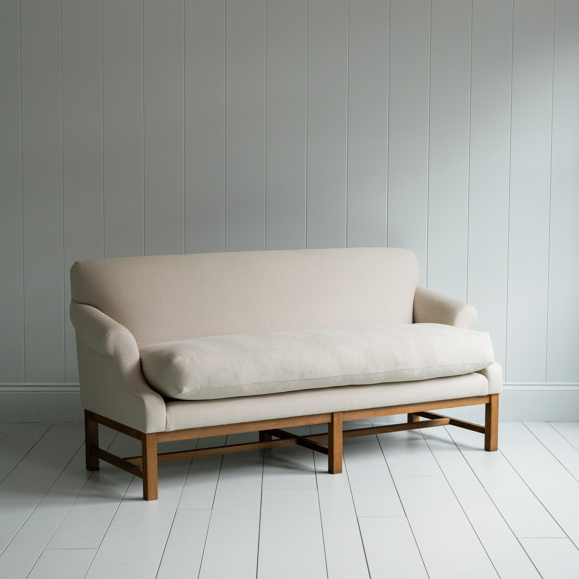  White couch on wooden floor in minimalist living room. 