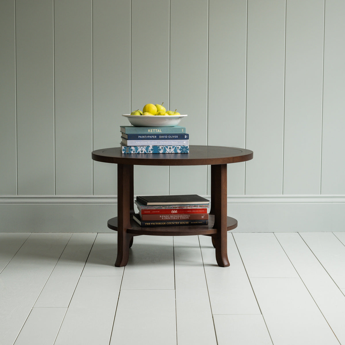 Round Perk coffee table in smoky stained oak with books and a plate of fruits, by Nicola Harding & Co.