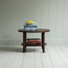 Round Perk coffee table in smoky stained oak with books and a plate of fruits, by Nicola Harding & Co.