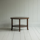 A round wooden coffee table with sturdy wooden base on the wooden floor - By NiX