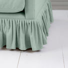 Curtain Call Love Seat close-up detail of the gathered ruffled skirt base and soft sage mineral linen fabric folds