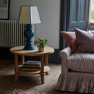 Perk Coffee Table, Oiled Oak With books and a blue base lamp next to a sofa in a living room - NiX Studio