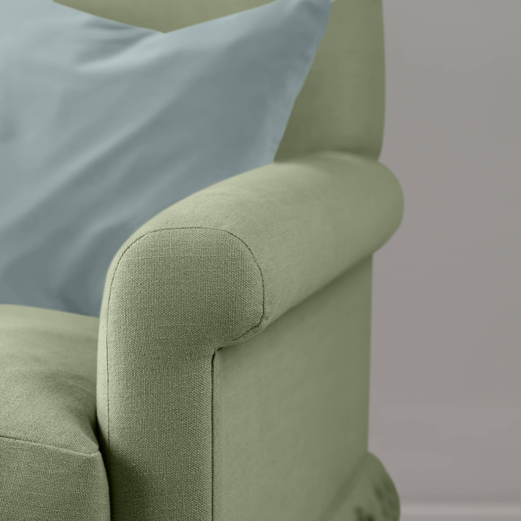  Closeup of armrest on the Moss Curtain Call sofa by NiX styled with a contrasting accent cushion. 