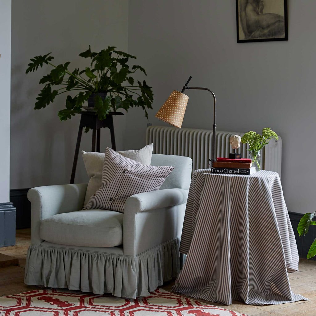  To The Point Floor Lamp Base in Waxed Brass, With Dotted Lampshade Next to a Side Table and an Curtain Call Arm Chair With 2 NiX Cushions - By NiX 