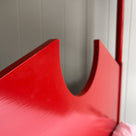 A red metal bed with a white pillow, providing comfort and style to any bedroom decor.