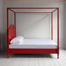 A red canopy bed with crisp white sheets, creating a serene and elegant atmosphere.