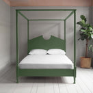 A green canopy bed with crisp white sheets, creating a serene and elegant atmosphere.