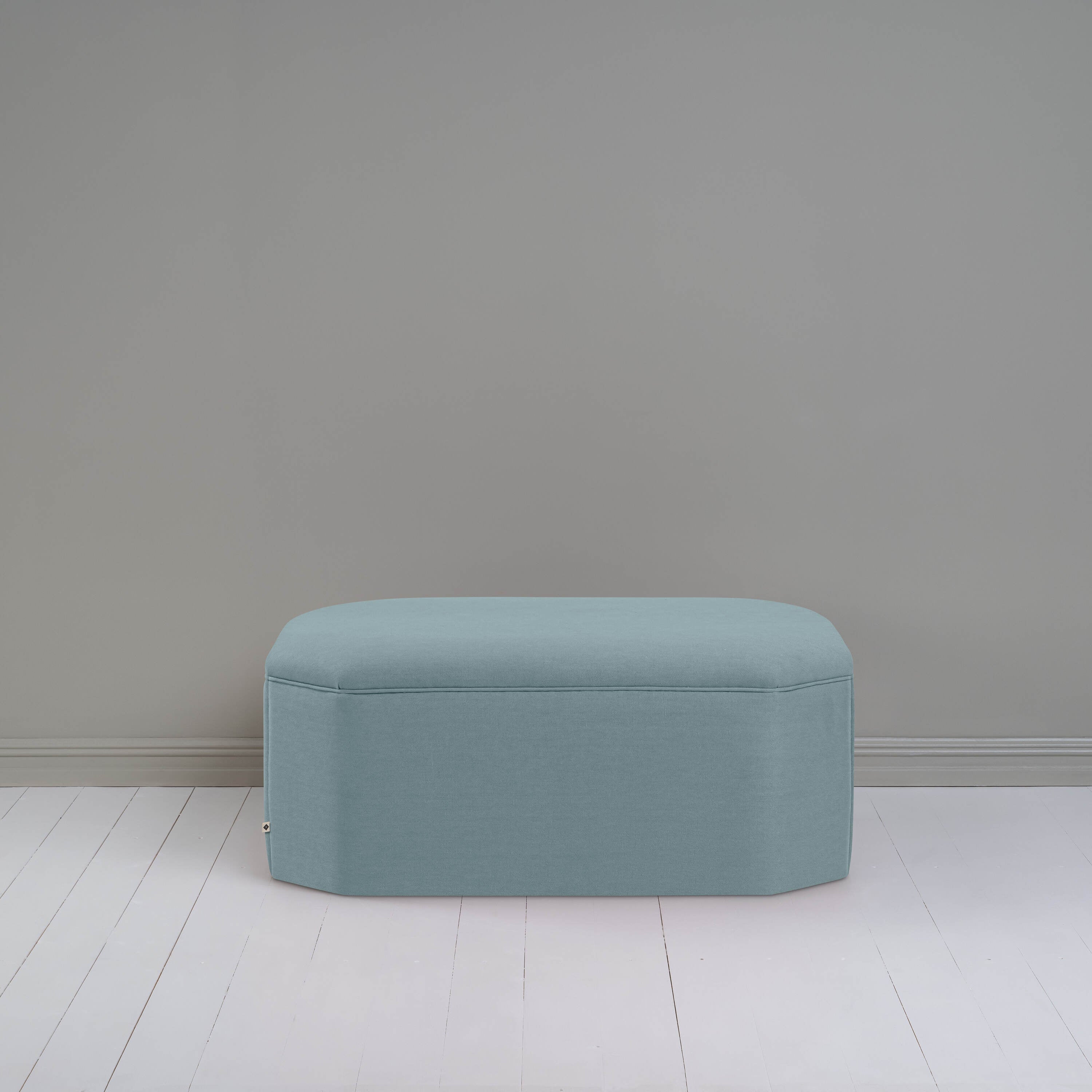  Small light blue ottoman in room with gray wall, adding cozy touch to modern decor. 