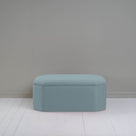 Small light blue ottoman in room with gray wall, adding cozy touch to modern decor.