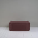 Small dark brown ottoman in room with gray wall, adding cozy touch to modern decor.