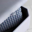 A close up of white and blue striped ottoman on a wooden floor, providing a stylish and practical storage solution.
