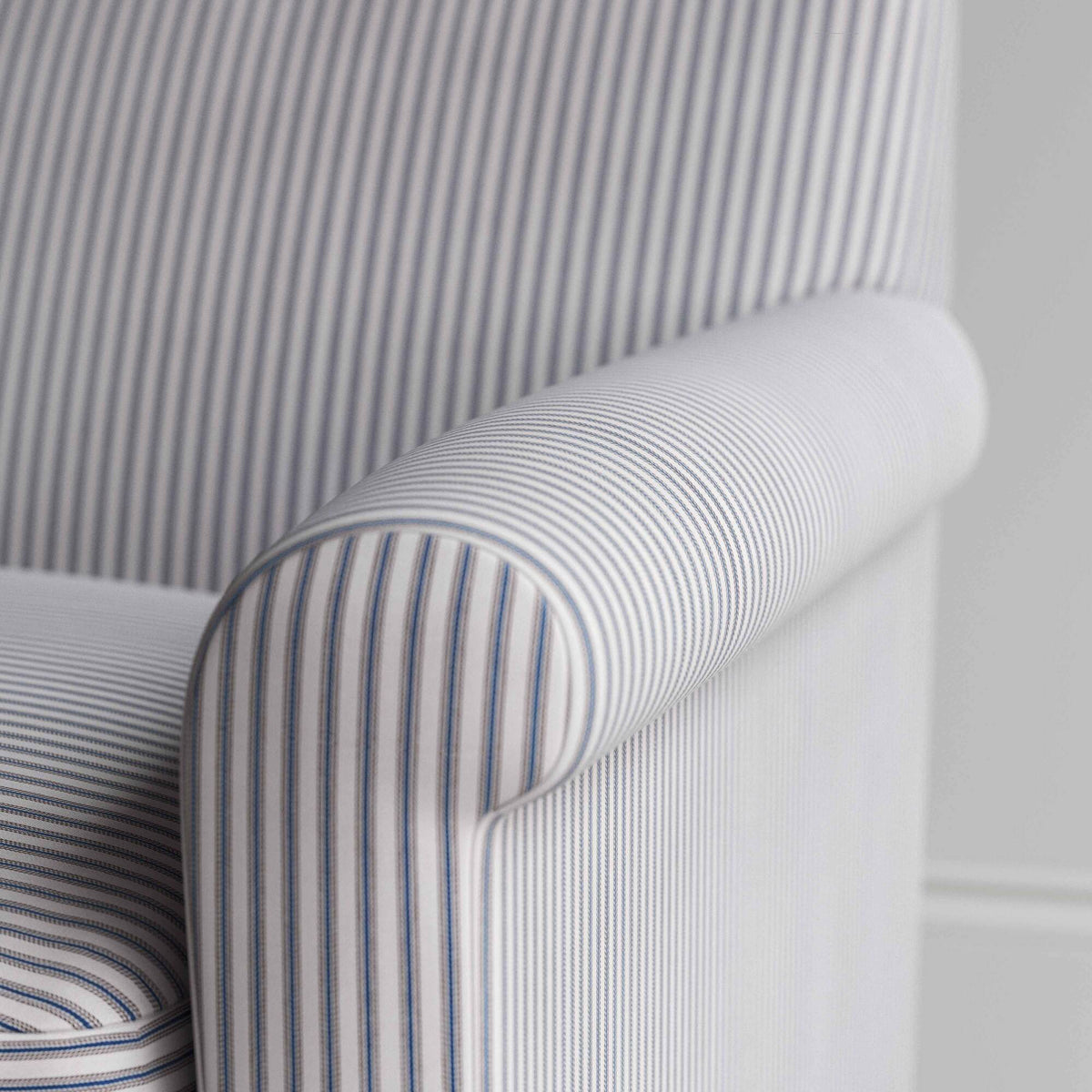 Close-up of the gracefully curved armrest on the Idler love seat in ticking cotton by Nix.
