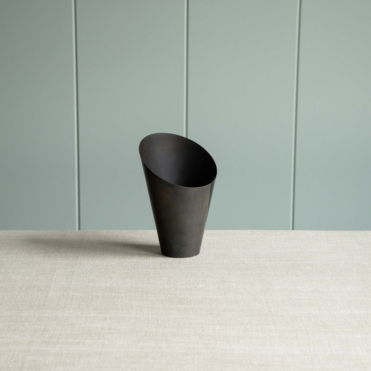 A black part of lamp against a green wall.