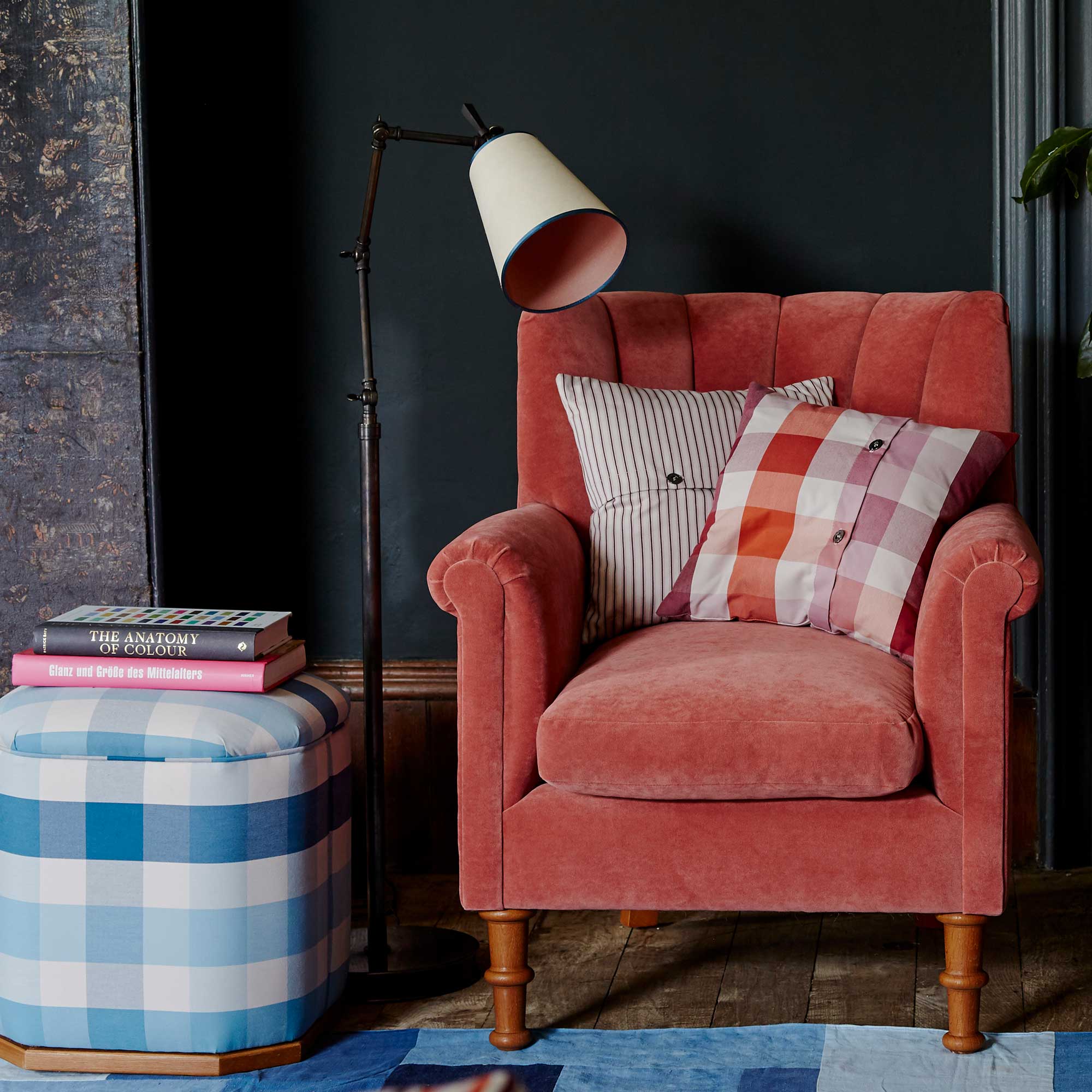  Brass Waxed Floor Lamp with To The Point Paper Empire Lamp Shade in Soft White with Peacock Blue Trim, next to an Ottoman with books and Armchair With Cushions - NiX by Nicola Harding & Co. 