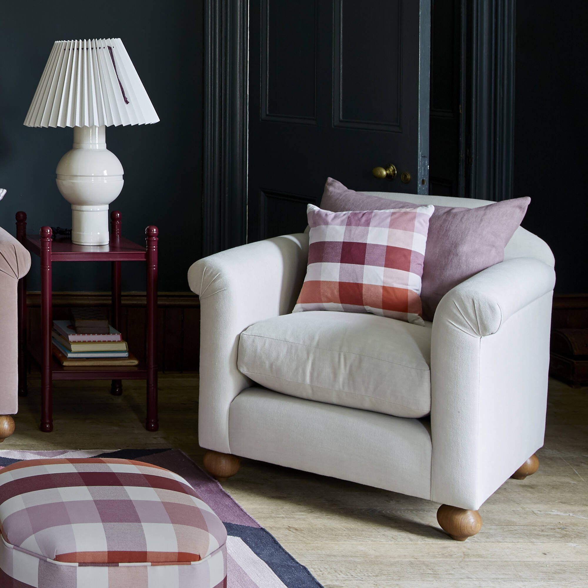  Nicola Harding interiors Dolittle armchair styled lifestyle scene with a checkered cushion and a ceramic table lamp 