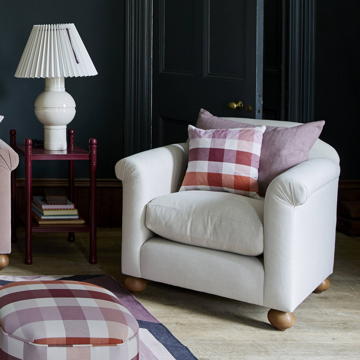 Nicola Harding interiors Dolittle armchair styled lifestyle scene with a checkered cushion and a ceramic table lamp