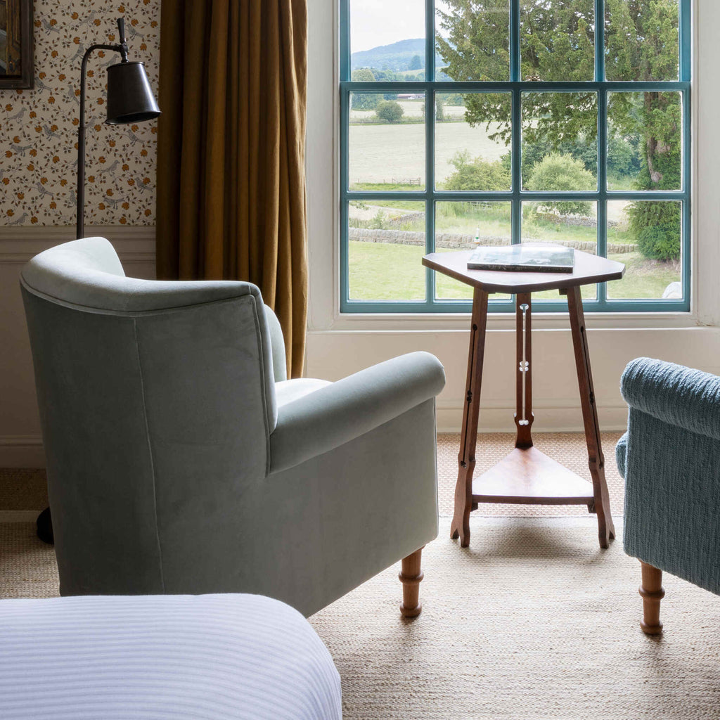  Time Out Armchair positioned by a large window looking out to a countryside view by Nicola Harding. 