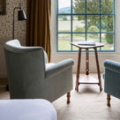 Time Out Armchair positioned by a large window looking out to a countryside view by Nicola Harding.