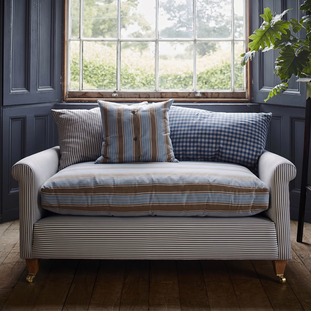  Idler love seat in ticking cotton styled in a bright British drawing room with window and decorative cushions by Nix. 