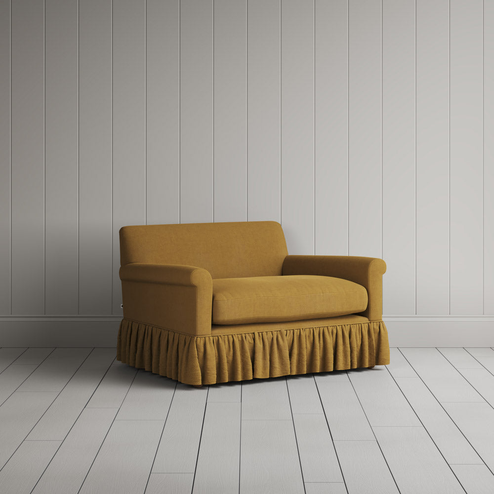  Nicola Harding interiors compact upholstered linen love seat with ruffled skirt base, angled studio view. 