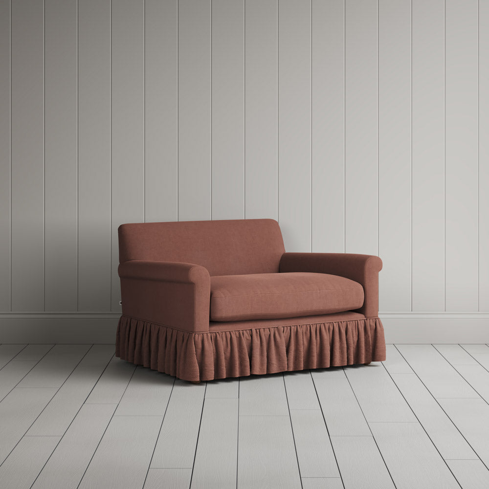  Nicola Harding interiors compact upholstered linen love seat with ruffled skirt base, angled studio view. 