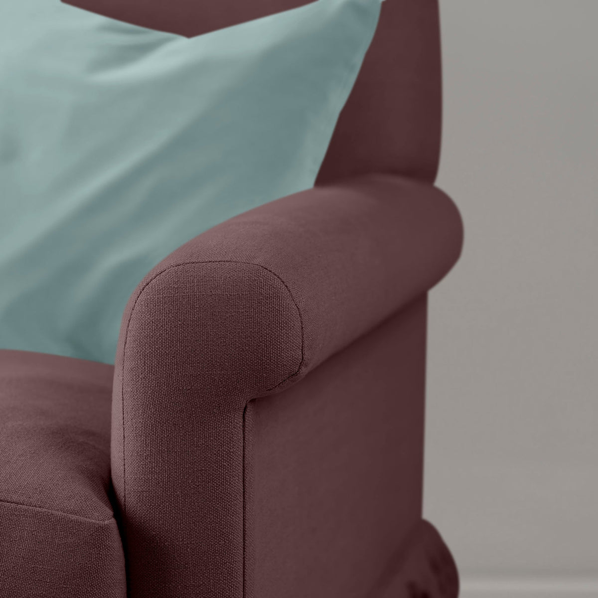 Detail of the armrest on the Damson Curtain Call sofa by NiX styled with a contrasting cushion.