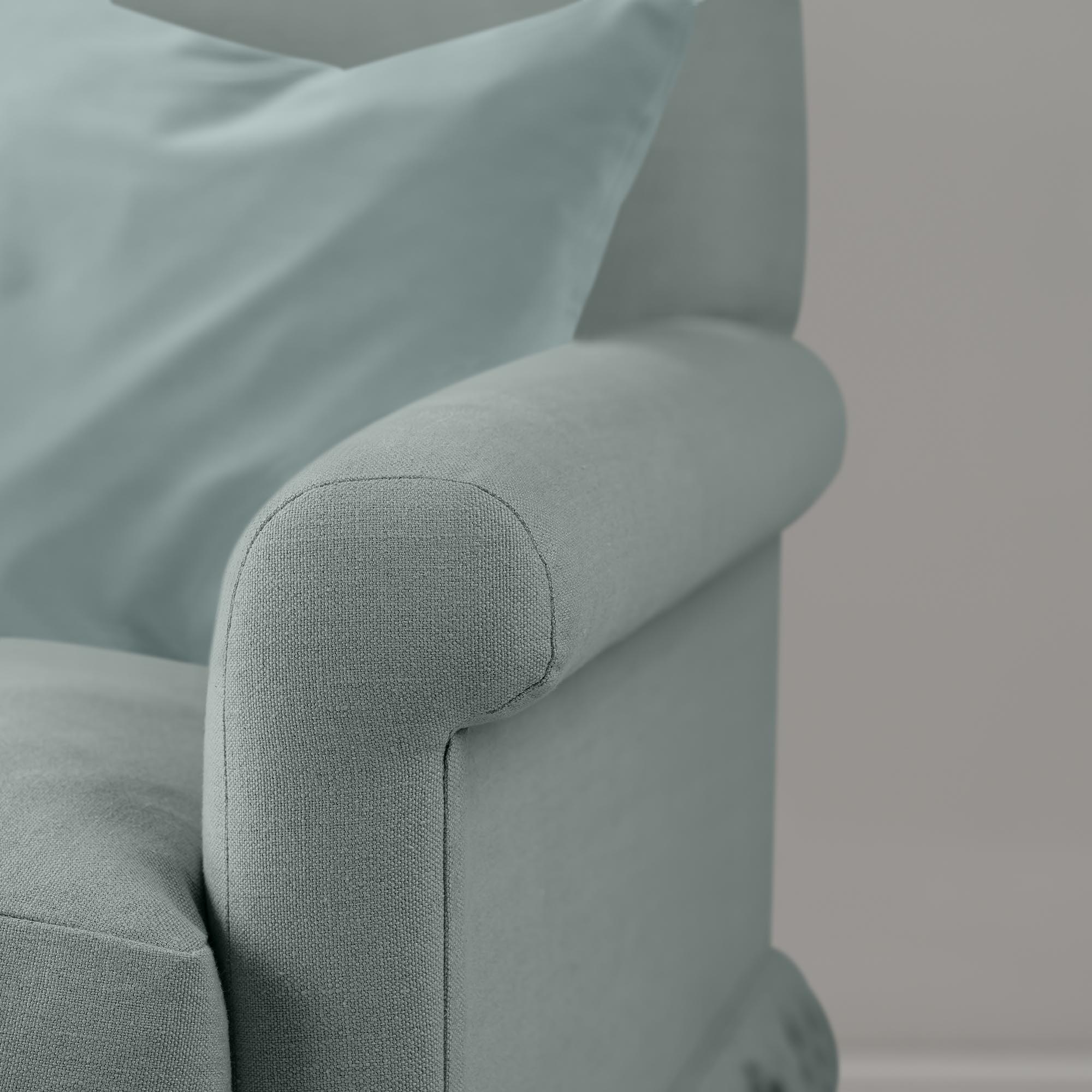  Close-up of premium linen upholstery on a Nicola Harding love seat with a decorative accent cushion. 