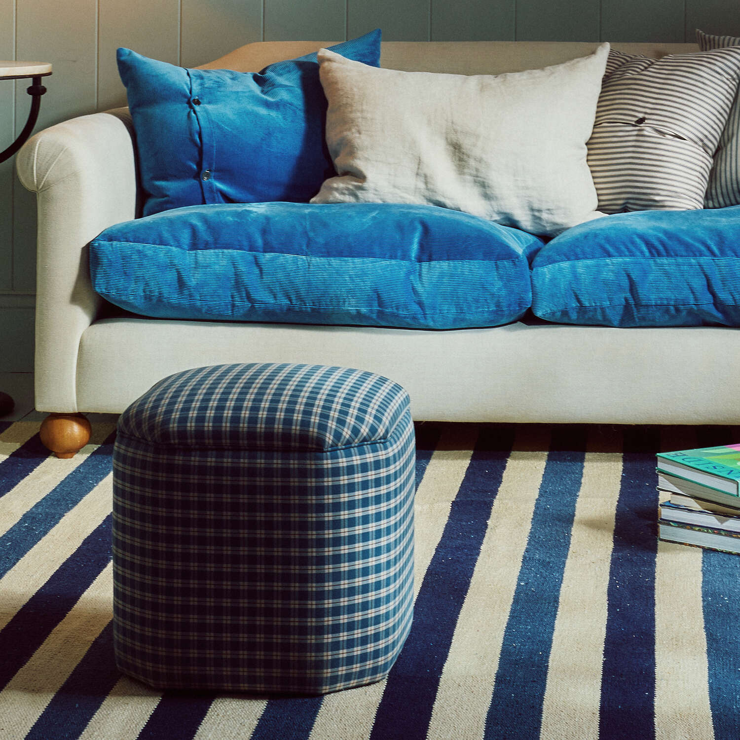  Nicola Harding interiors checkered upholstered ottoman and footstool styled in front of a blue corduroy love seat sofa - NiX furniture 