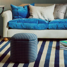 Nicola Harding interiors checkered upholstered ottoman and footstool styled in front of a blue corduroy love seat sofa - NiX furniture