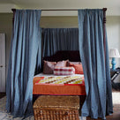 Elegant bedroom with a four-poster bed and curtains, designed by Nicola Harding & Co.