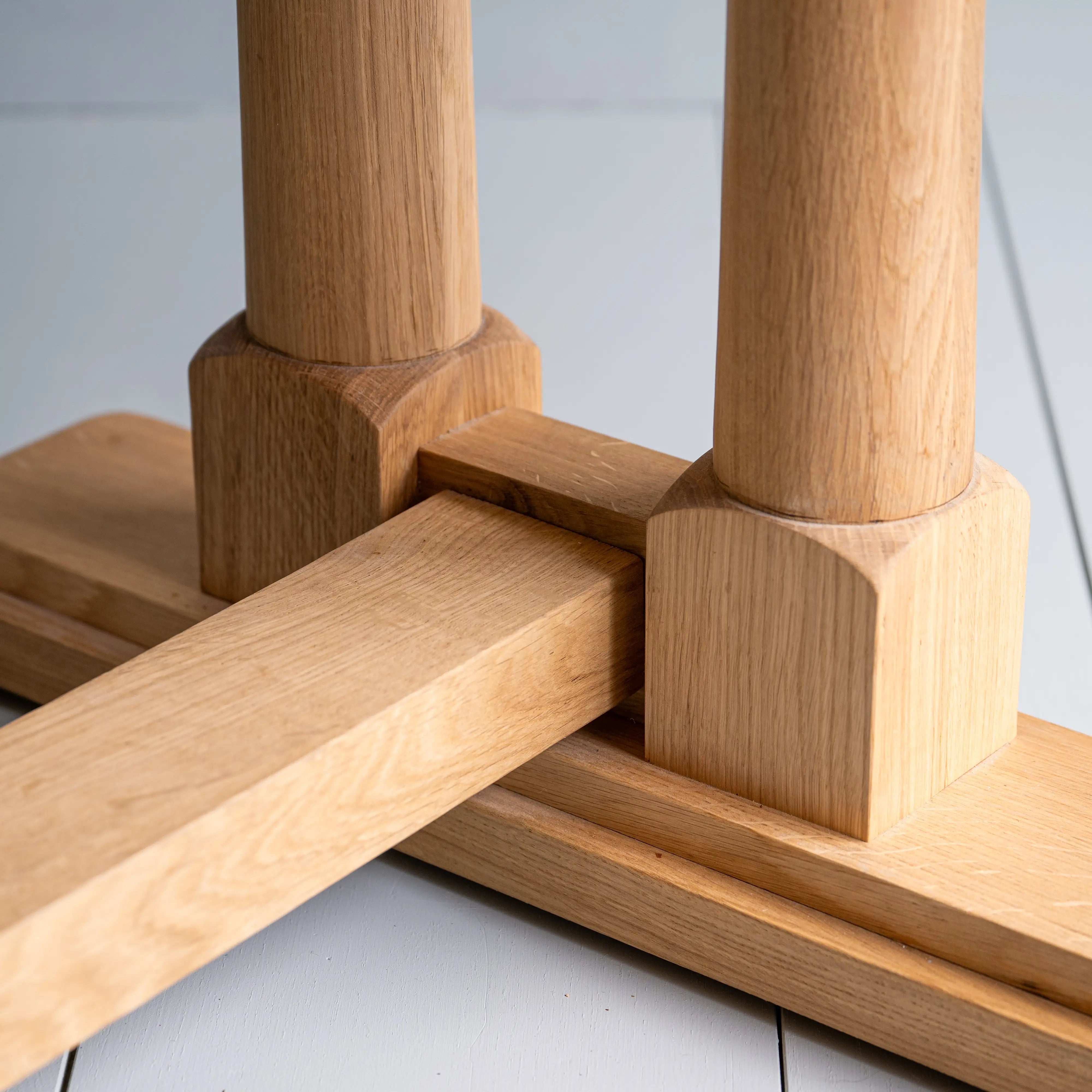  Close-up of the Tuck In rectangular dining table in oak with a strong, beautiful foot design, manufactured by NiX by Nicola Harding & Co. 