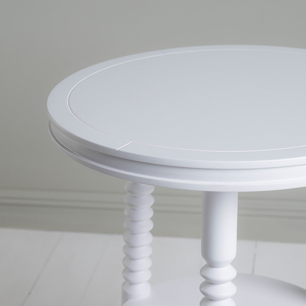 A close up of white round table with two legs.