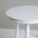 A close up of white round table with two legs.