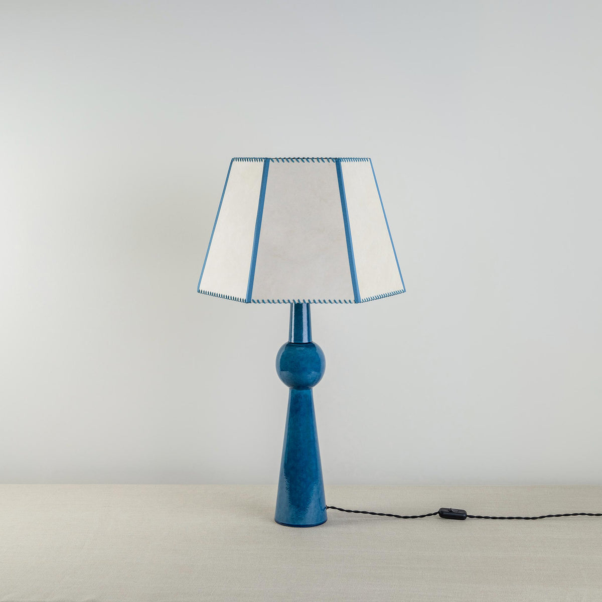 Comet Ceramic Table Lamp Base in Blue, With Townhouse Hexagonal Lamp Shade in Soft White with Peacock Blue Trim & Stitching - Nicola Harding