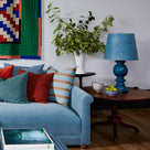 Hourglass Ceramic Table Lamp Base in Blue, With Humbug Straight Empire Batik Paper Lamp Shade in Dotty Sky Blue, On a Side Table Next To NiX Velvet Sofa - Nicola Harding