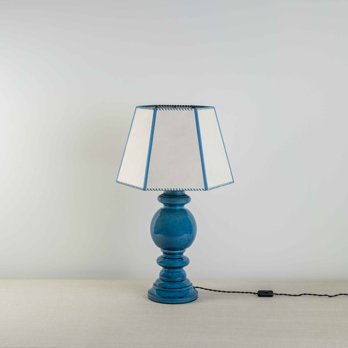 Hourglass Ceramic Table Lamp Base in Blue, With Townhouse Hexagonal Lamp Shade in Soft White with Peacock Blue Trim & Stitching - Nicola Harding
